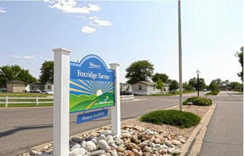 a sign in front of a street with houses in the background